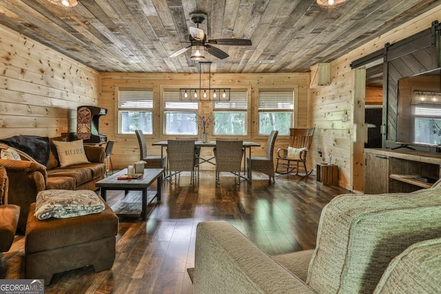 living room featuring dark wood-type flooring, wood walls, and a barn door