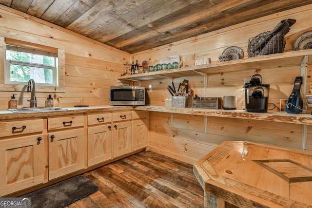 kitchen featuring vaulted ceiling, wooden walls, sink, and wooden ceiling