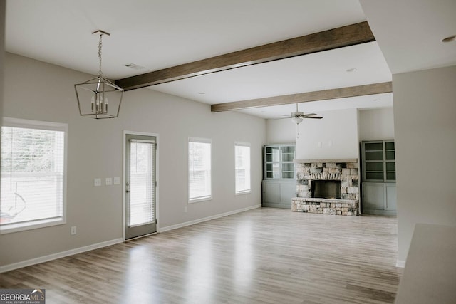 unfurnished living room with a fireplace, ceiling fan with notable chandelier, beam ceiling, and light hardwood / wood-style flooring