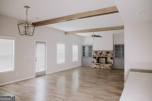 living room featuring beam ceiling, plenty of natural light, light wood-type flooring, and a fireplace