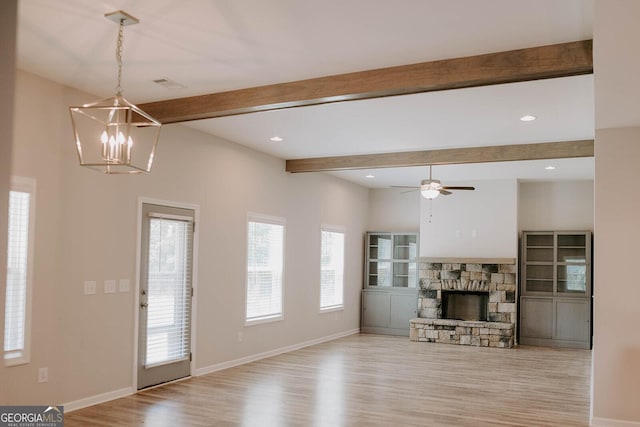 unfurnished living room with beamed ceiling, ceiling fan with notable chandelier, a fireplace, and light hardwood / wood-style floors