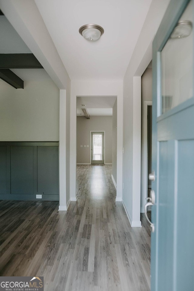 hallway with wood-type flooring and beam ceiling