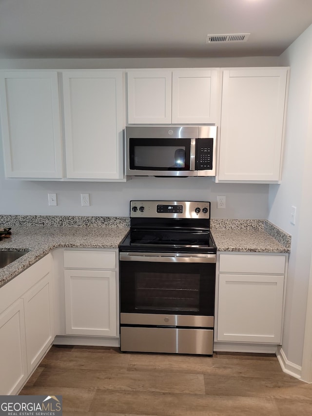 726 Windstream Dr Unit A10, Lagrange, GA 30241 - kitchen featuring light wood-type flooring, appliances with stainless steel finishes, white cabinets, and light stone countertops