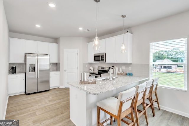 kitchen featuring a peninsula, light wood-type flooring, white cabinetry, and stainless steel appliances