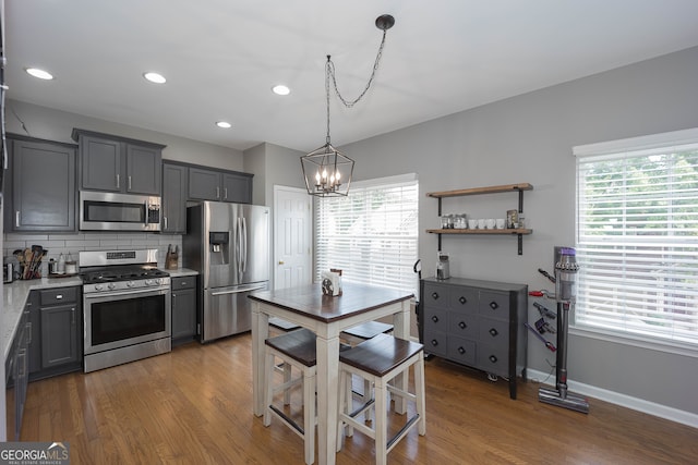 kitchen featuring appliances with stainless steel finishes, tasteful backsplash, hardwood / wood-style flooring, and a chandelier