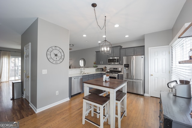 kitchen featuring light hardwood / wood-style floors, gray cabinetry, decorative backsplash, and stainless steel appliances