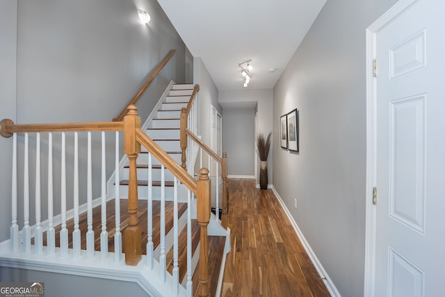 stairway with rail lighting and dark hardwood / wood-style flooring