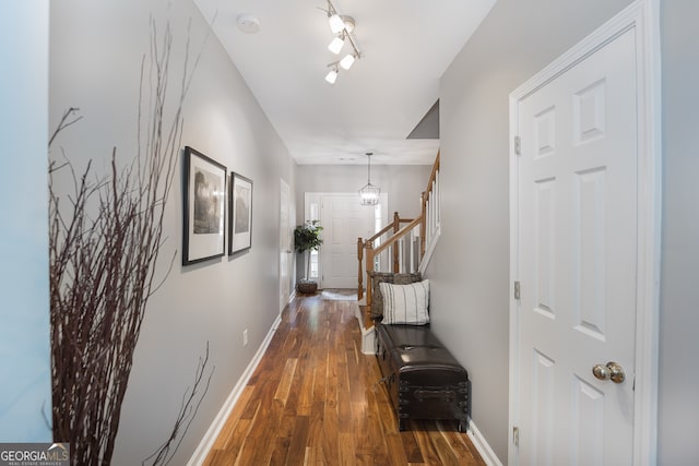 hallway with wood-type flooring, a notable chandelier, and track lighting