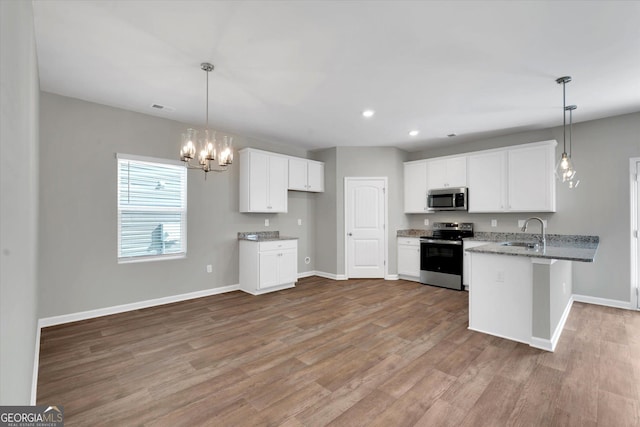 kitchen with pendant lighting, sink, stainless steel appliances, white cabinets, and kitchen peninsula