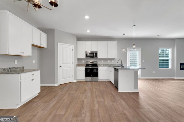 kitchen featuring white cabinetry, sink, hanging light fixtures, light stone counters, and stainless steel appliances