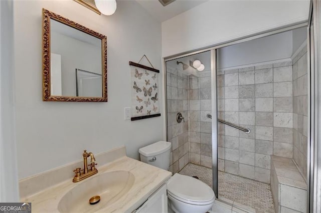 bathroom featuring tiled shower, toilet, and vanity