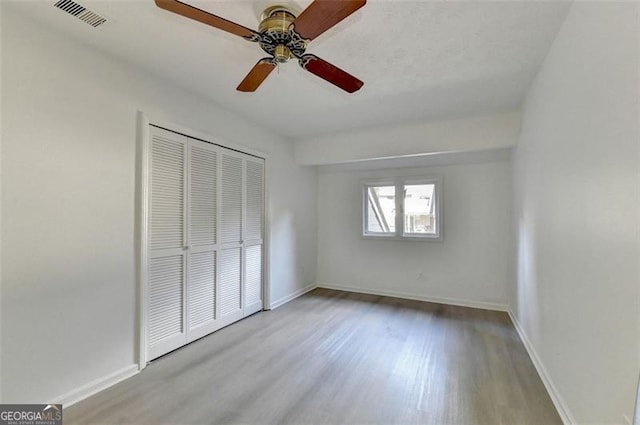 unfurnished bedroom with a closet, hardwood / wood-style floors, and ceiling fan