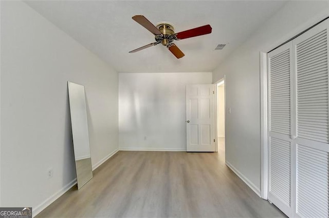 unfurnished bedroom with ceiling fan, light wood-type flooring, and a closet