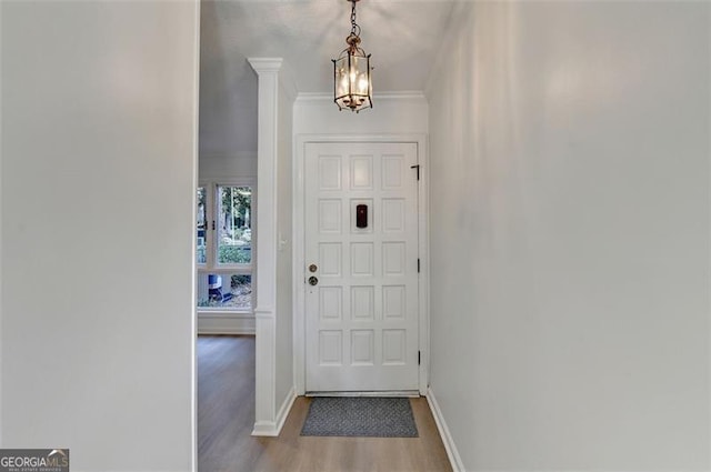 entryway with wood-type flooring, a chandelier, and ornamental molding