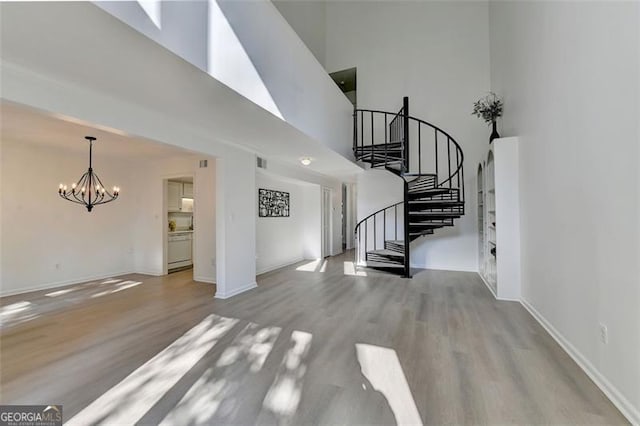 interior space featuring light wood-type flooring, a chandelier, and a towering ceiling