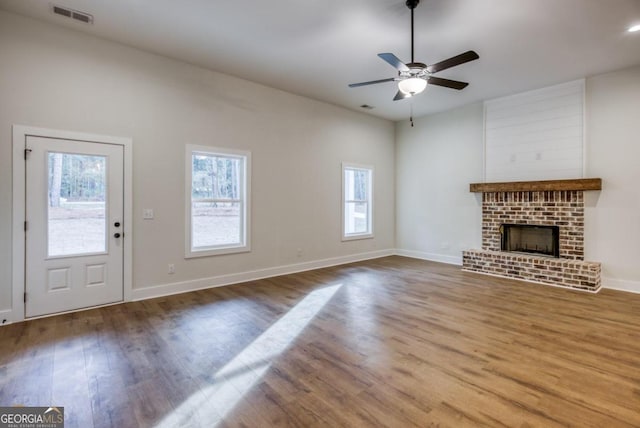 unfurnished living room featuring hardwood / wood-style flooring, a brick fireplace, and ceiling fan