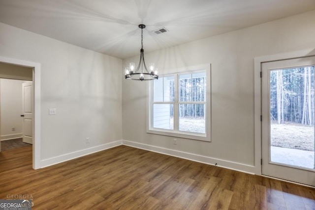 unfurnished dining area with dark hardwood / wood-style floors and an inviting chandelier