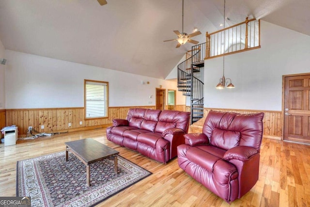 living room with high vaulted ceiling, ceiling fan with notable chandelier, and hardwood / wood-style floors