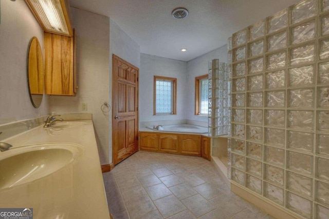 bathroom with a textured ceiling, double vanity, a tub to relax in, and tile patterned flooring