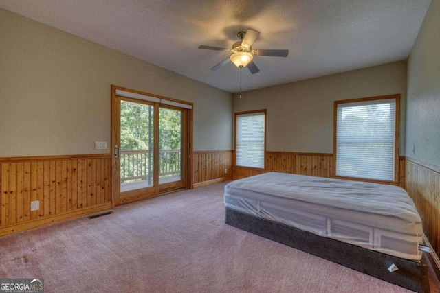 carpeted bedroom featuring ceiling fan, a textured ceiling, and access to exterior