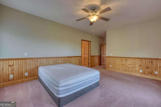 carpeted bedroom with ceiling fan and wooden walls