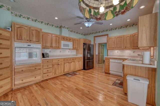 kitchen featuring ceiling fan, white appliances, sink, and light hardwood / wood-style floors