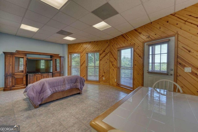 bedroom with a paneled ceiling, access to exterior, and light tile patterned floors