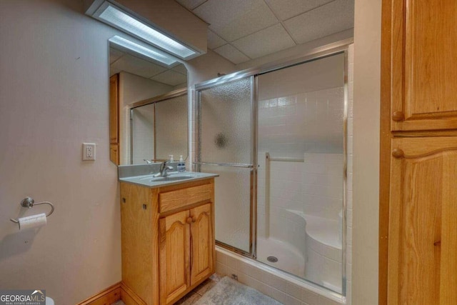 bathroom featuring an enclosed shower, vanity, and a drop ceiling