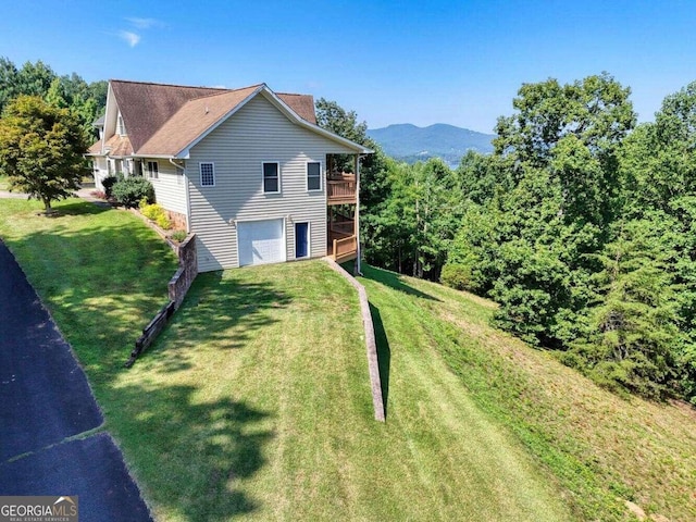 view of property exterior featuring a yard, a garage, and a deck with mountain view