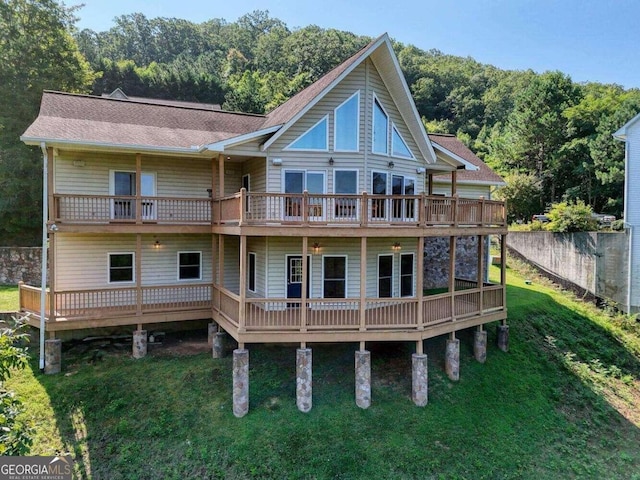 back of property with a wooden deck and a lawn