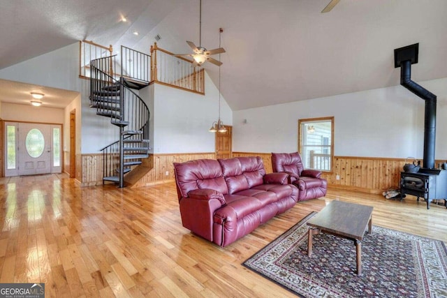 living room featuring high vaulted ceiling, wood-type flooring, ceiling fan, a wood stove, and a wealth of natural light