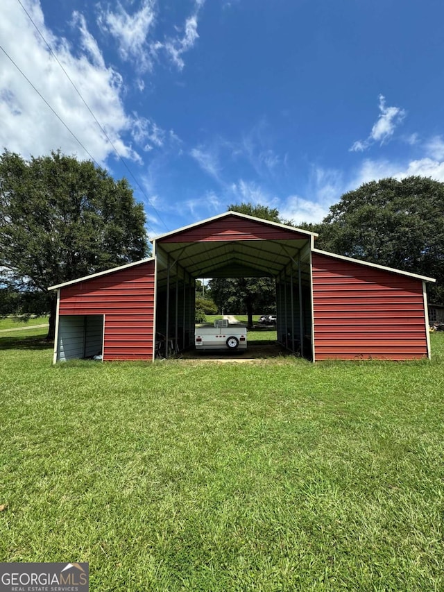 view of outdoor structure with a carport and a yard