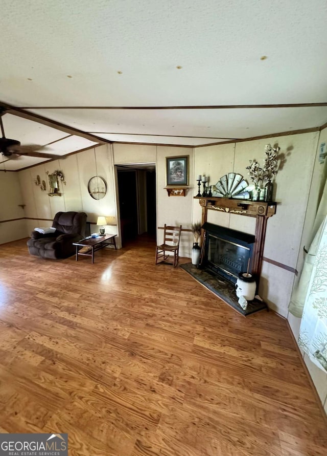 living room with a textured ceiling, lofted ceiling with beams, hardwood / wood-style floors, and ceiling fan