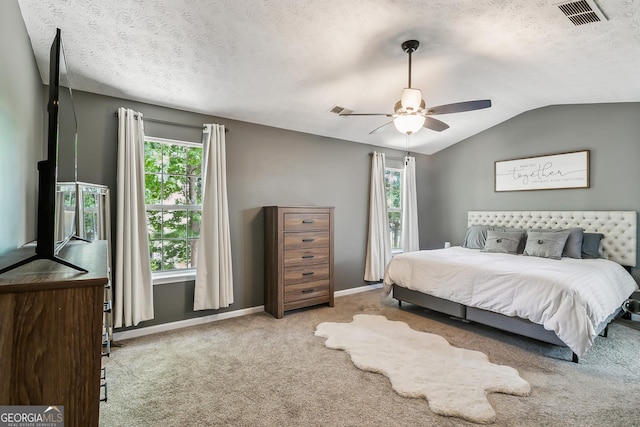 bedroom with multiple windows, lofted ceiling, light carpet, and a textured ceiling