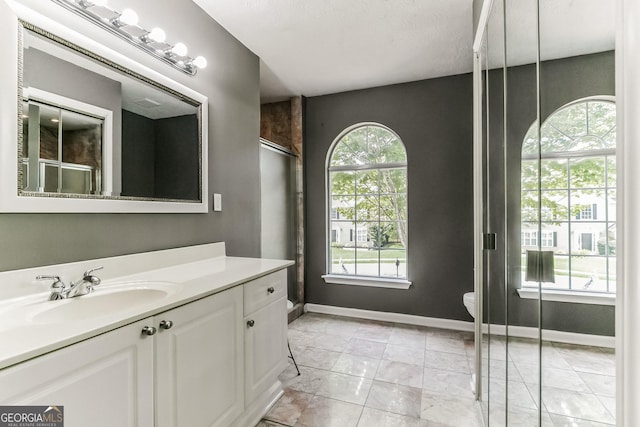 bathroom with walk in shower, vanity, toilet, and tile patterned flooring