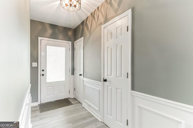 doorway to outside with a notable chandelier and light hardwood / wood-style floors