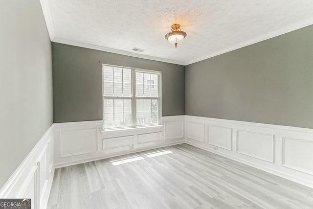 unfurnished room featuring crown molding, a textured ceiling, and light wood-type flooring