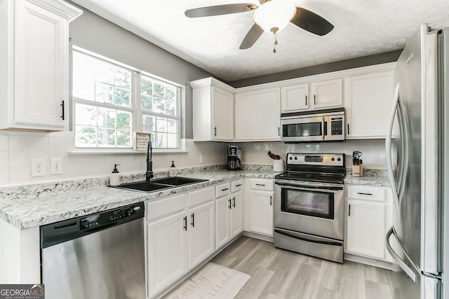 kitchen featuring white cabinetry, sink, stainless steel appliances, and light hardwood / wood-style floors