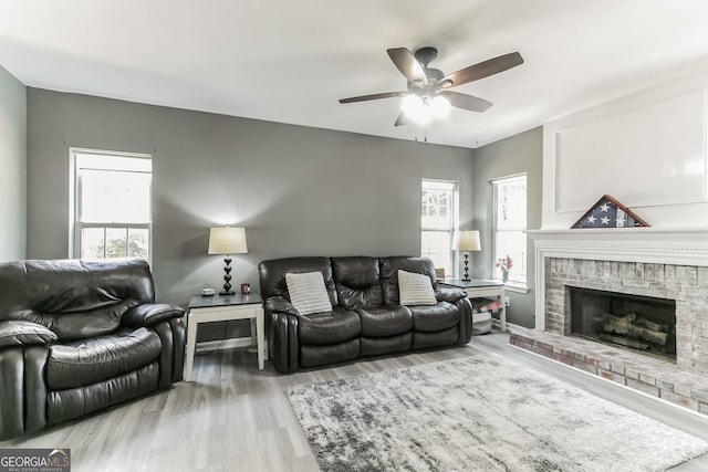 living room with ceiling fan, wood-type flooring, and a fireplace