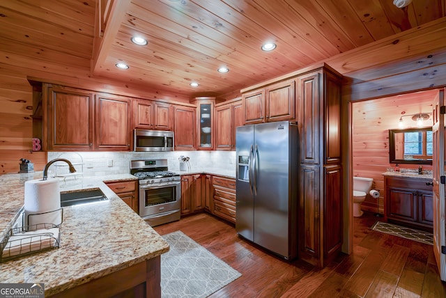 kitchen featuring light stone countertops, dark wood-type flooring, stainless steel appliances, and wooden walls