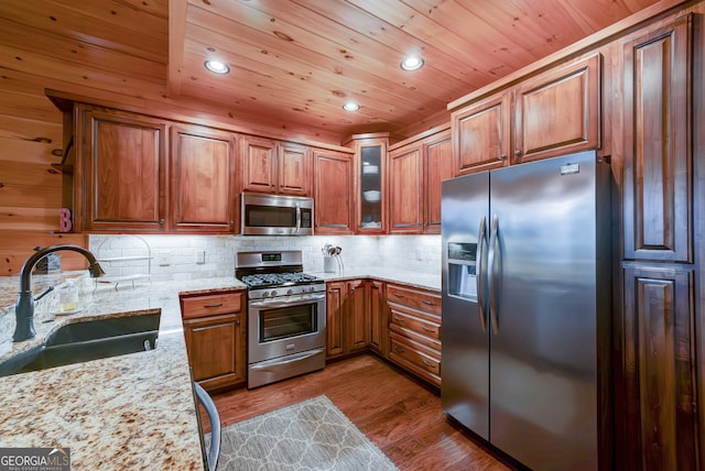 kitchen featuring dark hardwood / wood-style flooring, light stone countertops, backsplash, stainless steel appliances, and sink