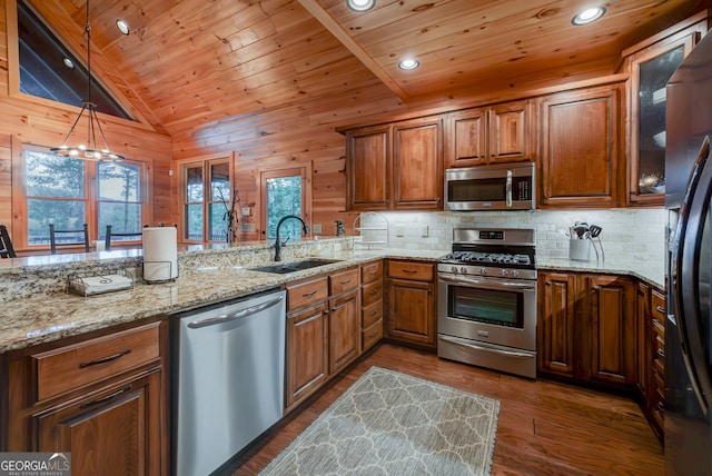 kitchen featuring dark hardwood / wood-style flooring, hanging light fixtures, appliances with stainless steel finishes, vaulted ceiling, and sink