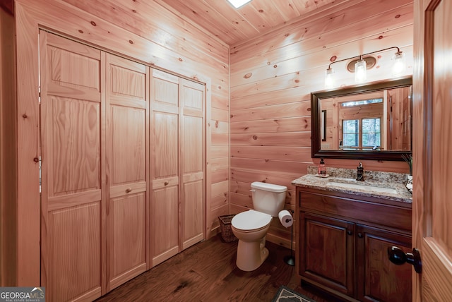 bathroom featuring wooden walls, vanity, toilet, and hardwood / wood-style floors