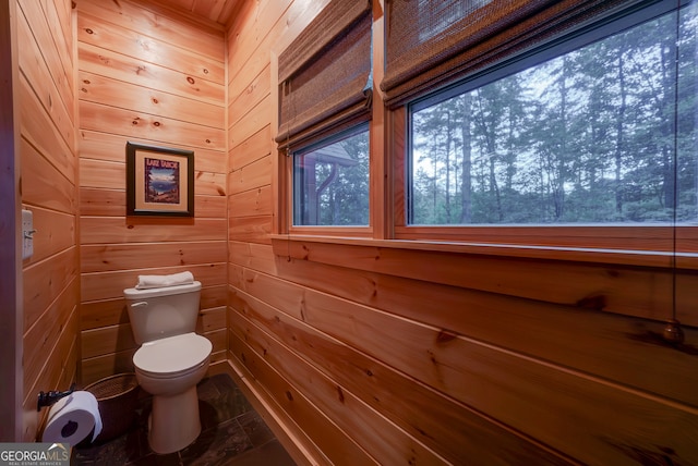 bathroom with wood walls, toilet, and tile patterned floors