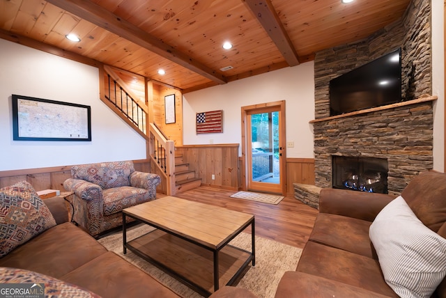 living room with beam ceiling, wooden ceiling, a stone fireplace, and hardwood / wood-style floors