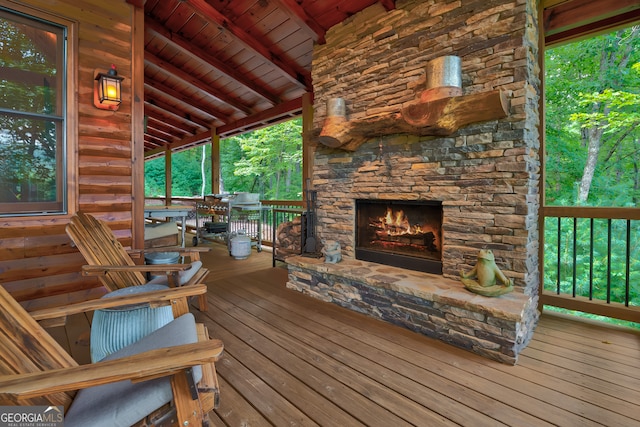 wooden terrace featuring a stone fireplace