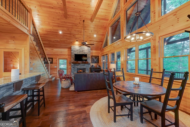 dining room with wood walls, a stone fireplace, hardwood / wood-style flooring, and a healthy amount of sunlight