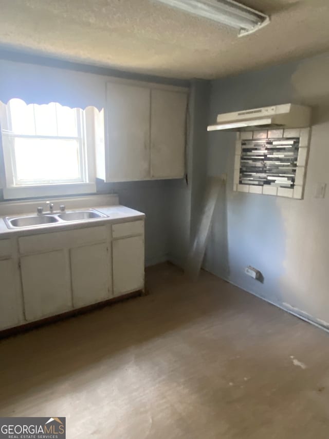 kitchen with sink, a textured ceiling, and white cabinetry