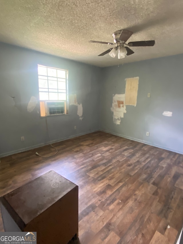 spare room featuring hardwood / wood-style floors, cooling unit, a textured ceiling, and ceiling fan