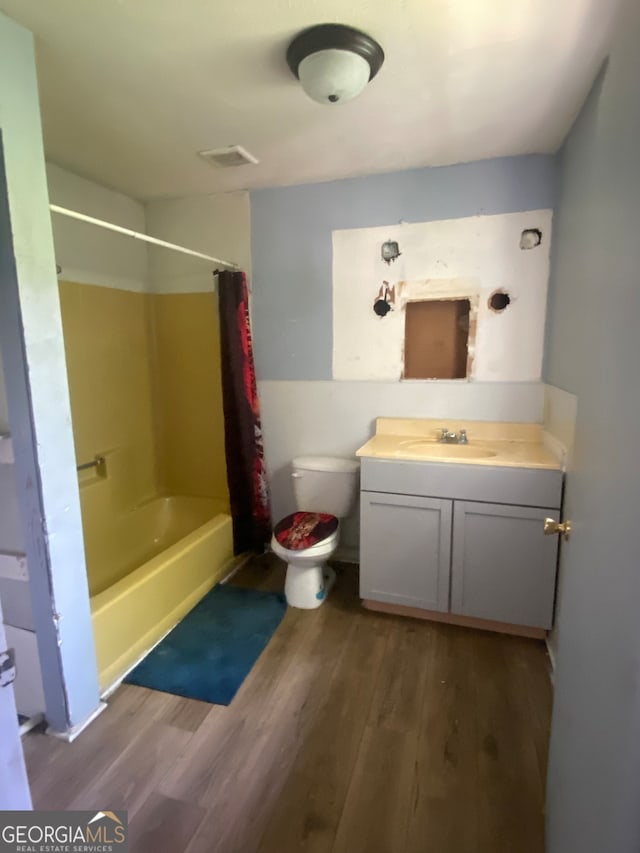 full bathroom featuring hardwood / wood-style floors, shower / bath combo with shower curtain, vanity, and toilet